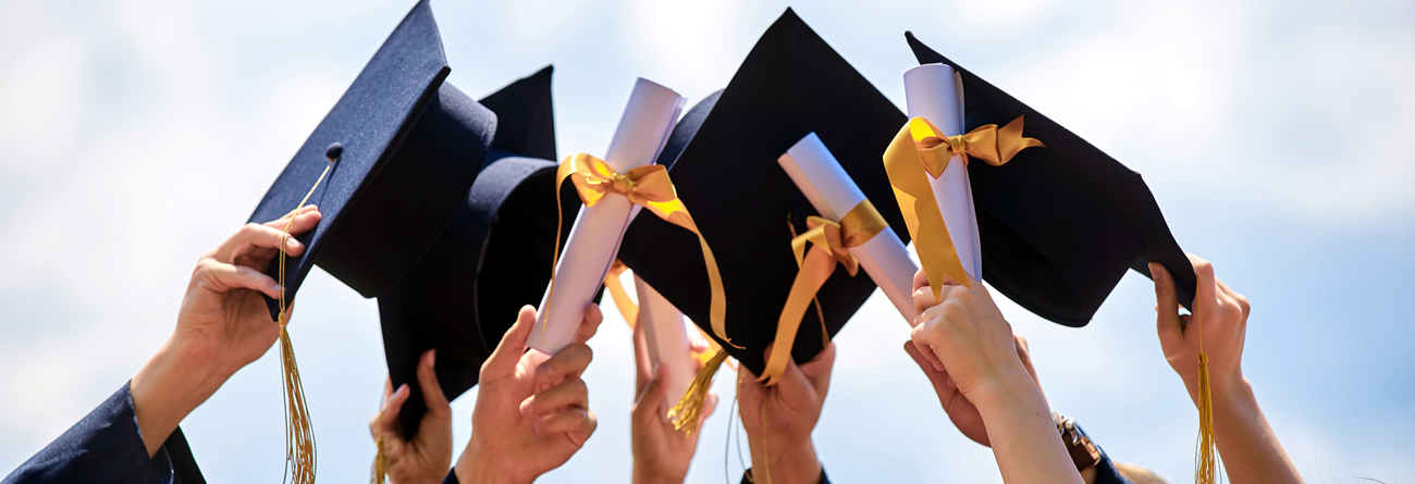 Several hands holding mortarboards and diplomas